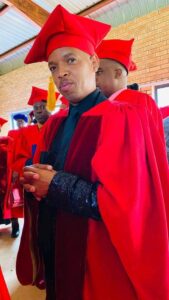 A man in red graduation robes standing in front of a group of people, who is a ZCC SINGER.