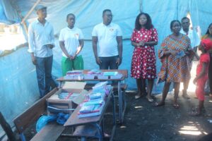 A group of people from the beira district youth council standing in front of a tent, distributing and organizing school supplies.
