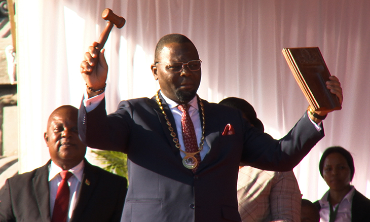 The mayor of Maputo, dressed in a suit, holds a hammer.